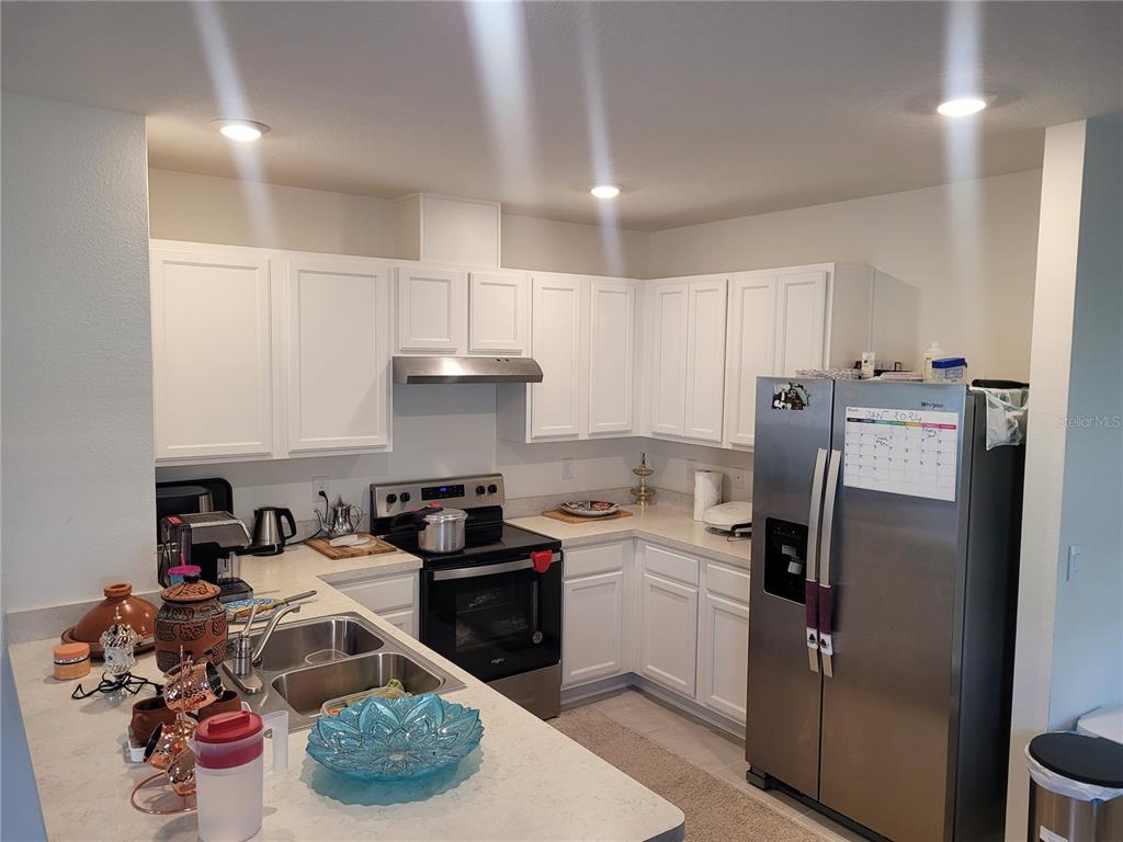 A kitchen with white cabinets, stainless steel appliances, and light-colored countertops — 2763 REDDISH EGRET BEND, HARMONY, FL