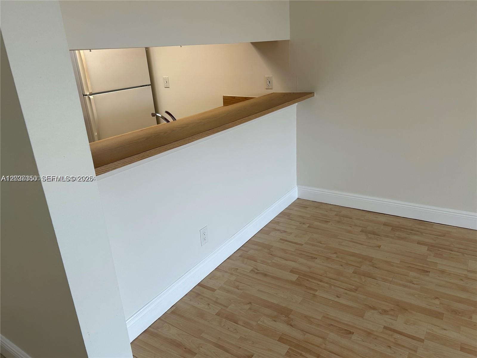 A kitchen pass-through window with a wood countertop overlooks a room with light flooring — 8600 N Sherman Cir # 504, Miramar FL 33025, MIRAMAR, FL