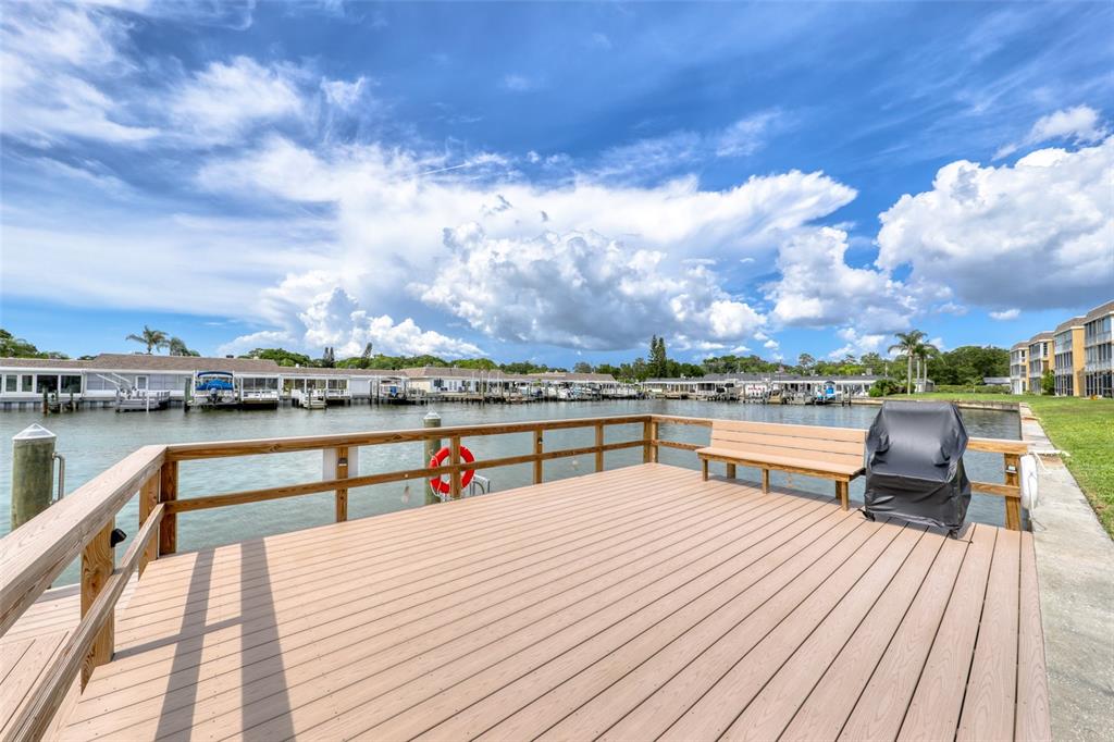 A wooden deck with a bench and a covered grill overlooks a boat dock — 1 BOCA CIEGA POINT BOULEVARD UNIT 316, ST PETERSBURG, FL