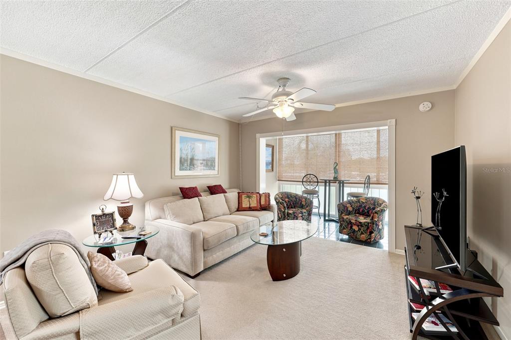 A living room features a beige sofa, patterned armchairs, a glass coffee table, and a balcony — 1 BOCA CIEGA POINT BOULEVARD UNIT 316, ST PETERSBURG, FL