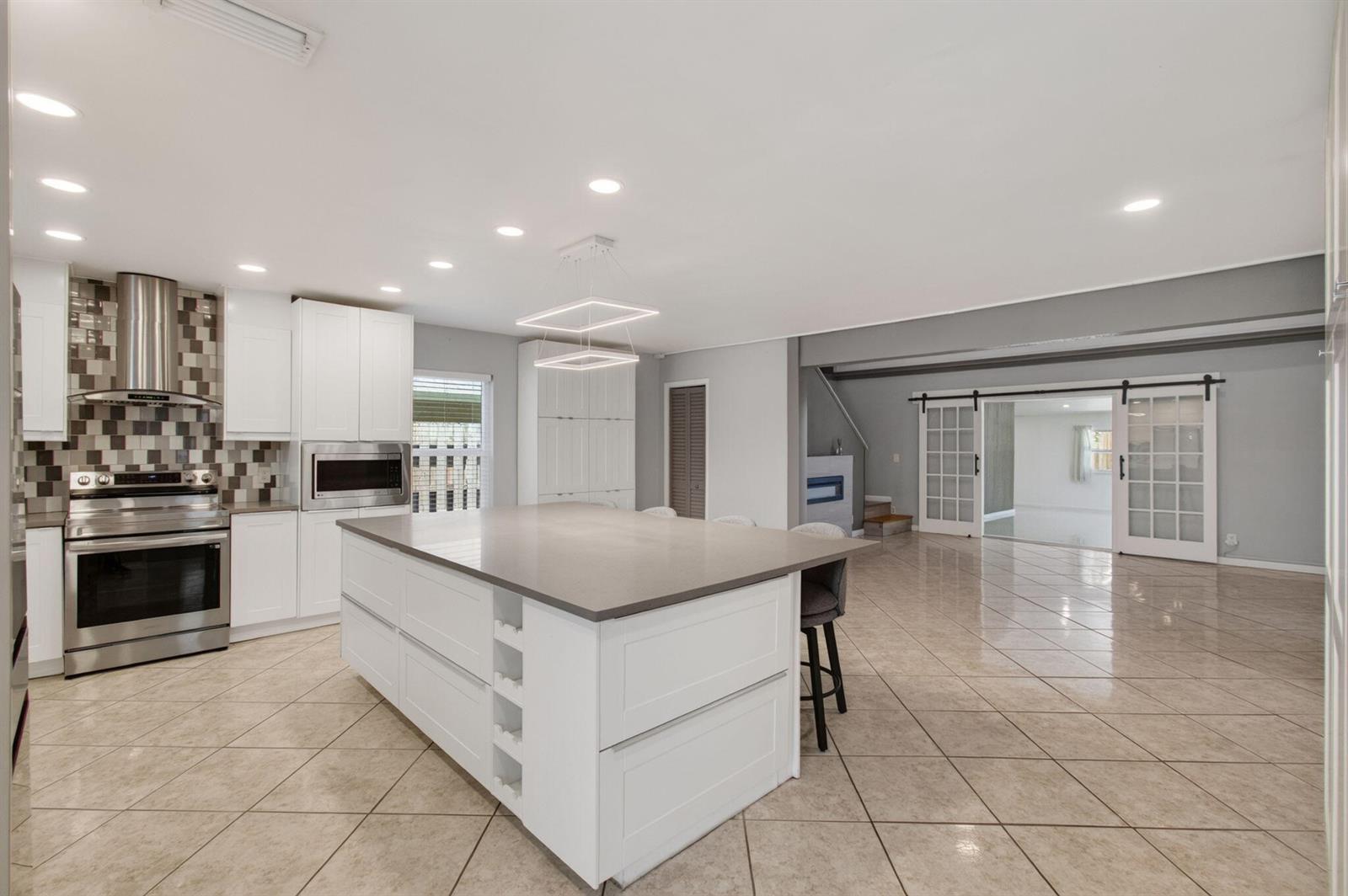 A kitchen with white cabinets, a large island, stainless steel appliances, and tiled flooring — 2388 Zeder Avenue, Delray Beach FL 33444, DELRAY BEACH, FL