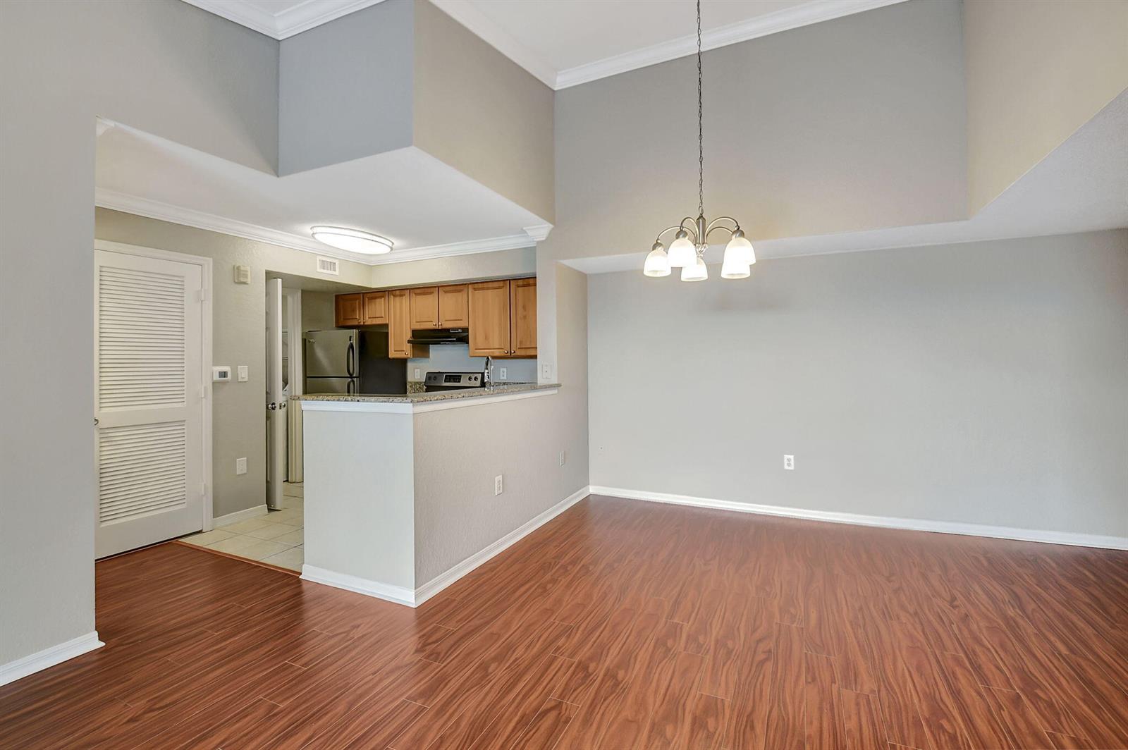 A dining area with wood-look flooring opens to a kitchen featuring wood cabinets and appliances — 15065 Michelangelo Boulevard # 305, Delray Beach FL 33446, DELRAY BEACH, FL