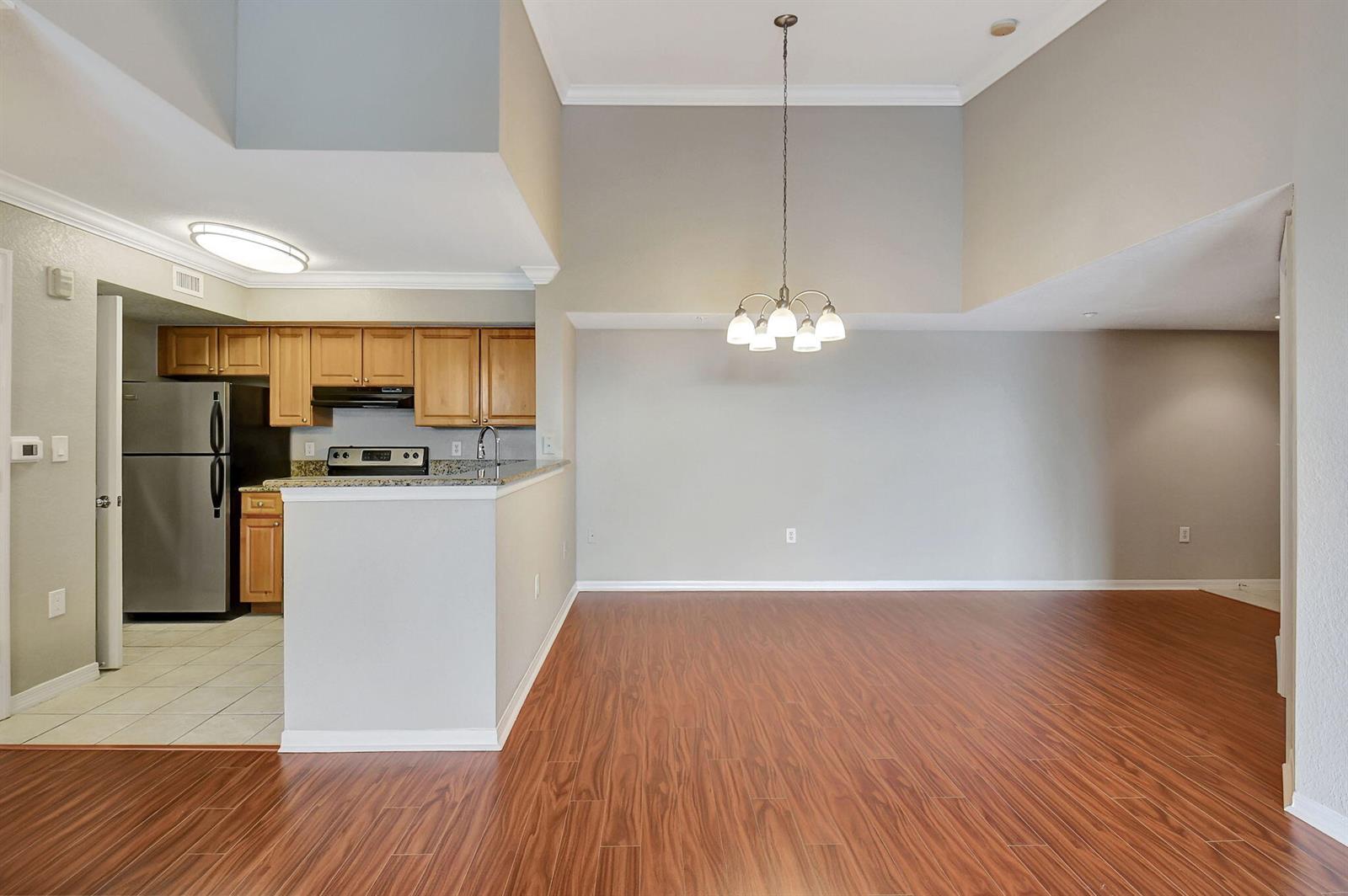 A kitchen with wood cabinets and stainless steel appliances opens to a dining area — 15065 Michelangelo Boulevard # 305, Delray Beach FL 33446, DELRAY BEACH, FL