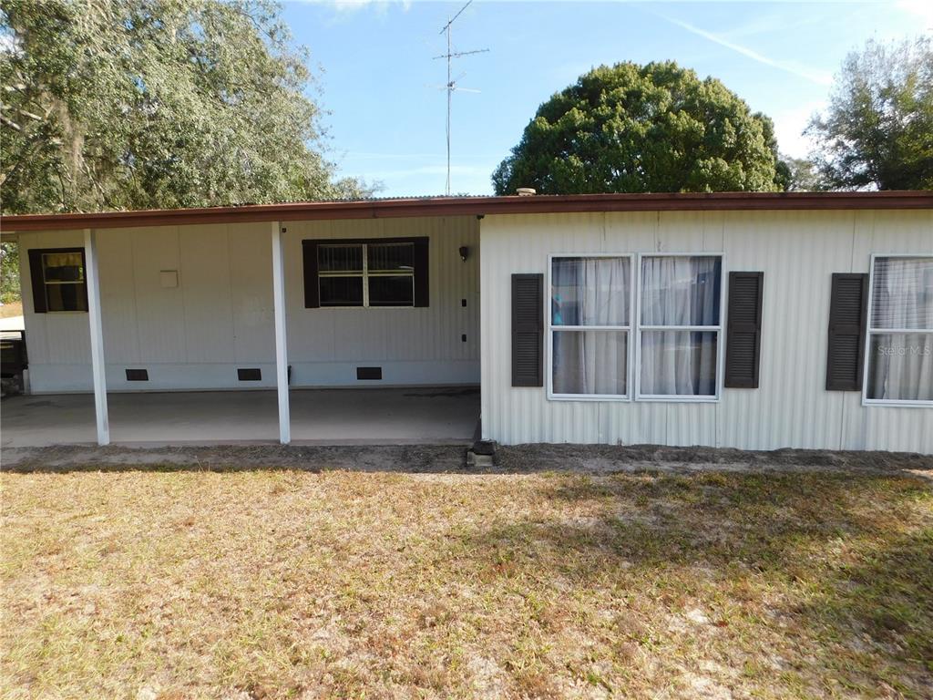 A single-story manufactured home with a covered carport and white vertical siding — 34912 HAWKIOWA ROAD, DADE CITY, FL