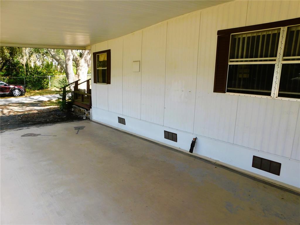 A covered carport area with white exterior siding and a window on the side — 34912 HAWKIOWA ROAD, DADE CITY, FL