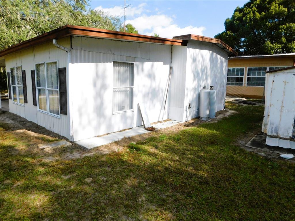 The exterior of a white mobile home features brown trim, several windows, and propane tanks — 34912 HAWKIOWA ROAD, DADE CITY, FL