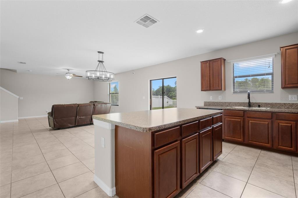 A kitchen with a large island and dark wood cabinets overlooks an open living area — 36101 STABLE WILK AVENUE, ZEPHYRHILLS, FL
