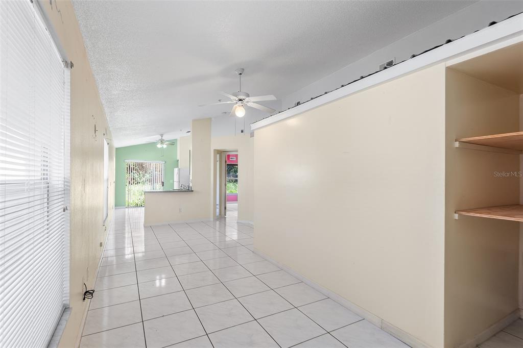 A long, tiled room features white walls, two ceiling fans, and windows with blinds — 9616 HOLLYHILL DRIVE, ORLANDO, FL