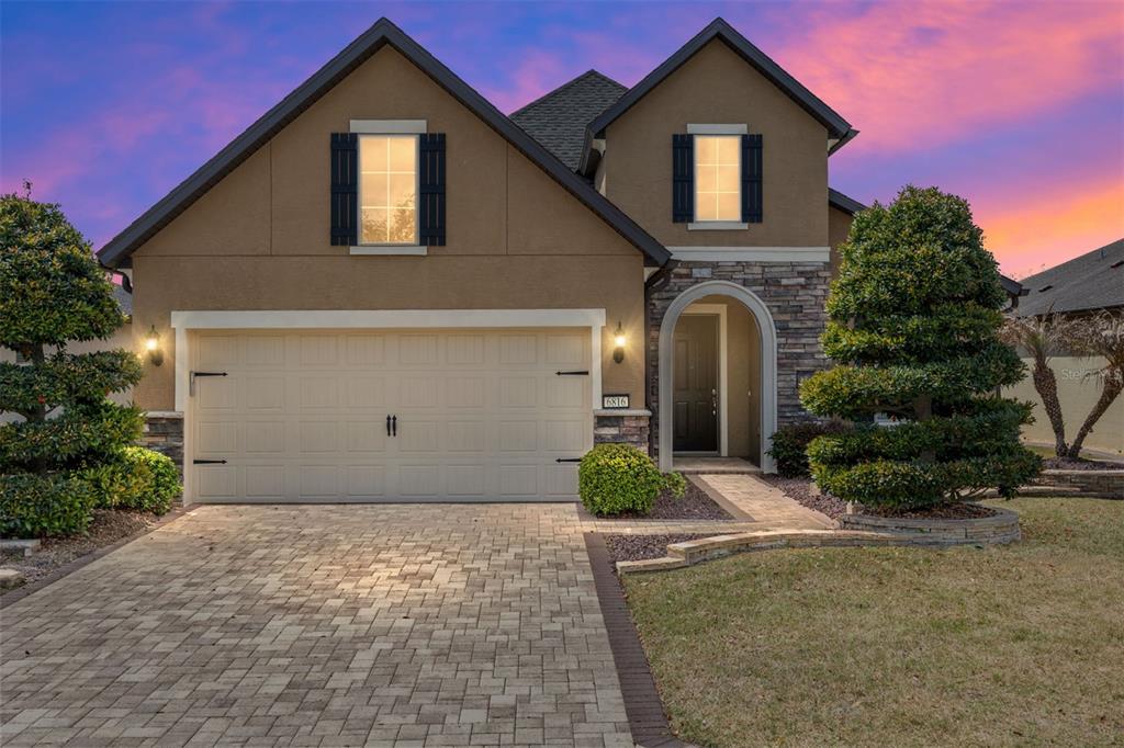 A two-story suburban house with a stone facade, arched entryway, and a paved driveway — 6816 SW 95TH CIRCLE, OCALA, FL