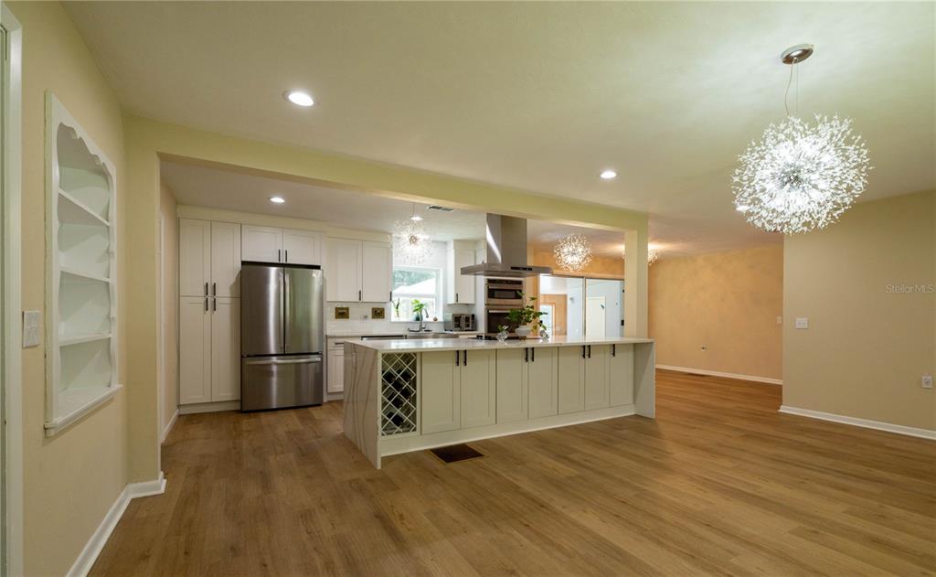 A modern kitchen features white cabinetry, a waterfall island, stainless steel appliances, and wood flooring — 298 N COURT STREET, BRONSON, FL