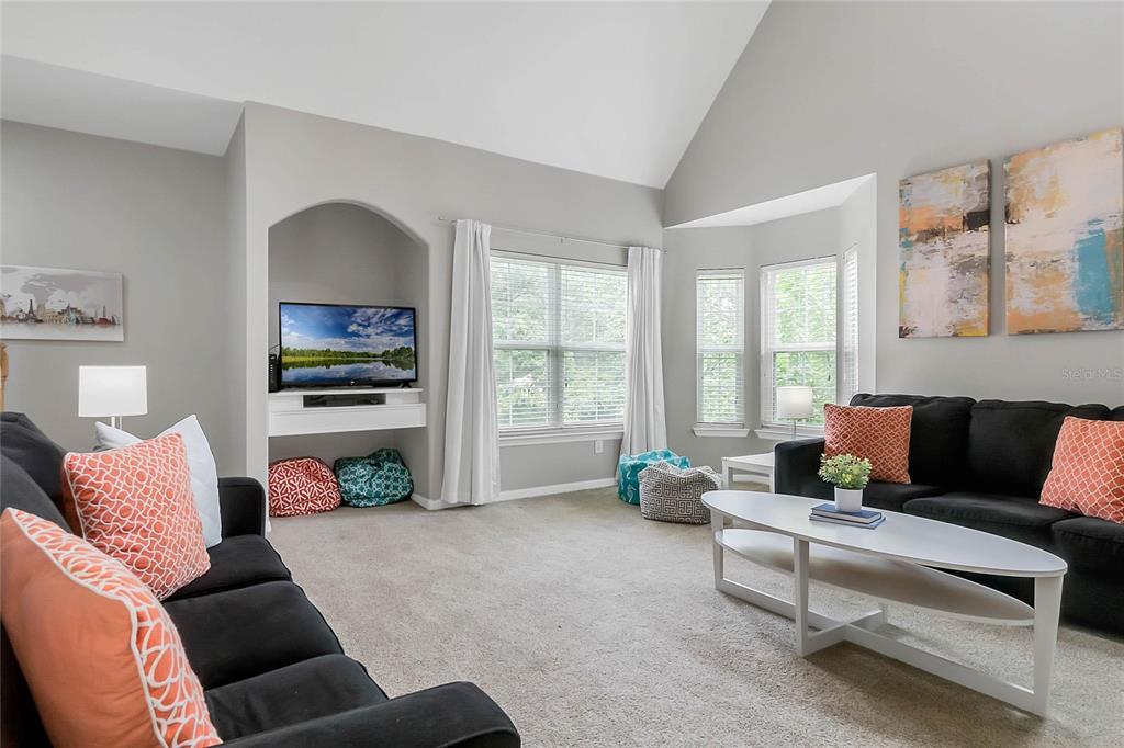 A living room features a vaulted ceiling, gray walls, carpeted floors, and two black sofas — 3017 BONFIRE BEACH DRIVE UNIT 203, KISSIMMEE, FL