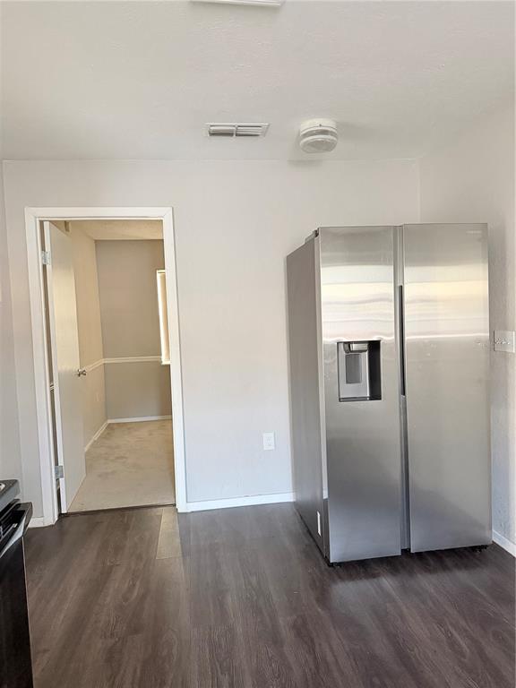 A stainless steel refrigerator stands in a room with dark wood-look flooring and an open doorway — 878 KILLEARN BOULEVARD, WINTER HAVEN, FL