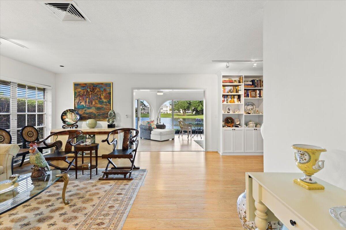 A living room with light wood floors, a built-in bookshelf, and a view of a lake — 233 Rio Vista Circle # 233, Atlantis FL 33462, ATLANTIS, FL