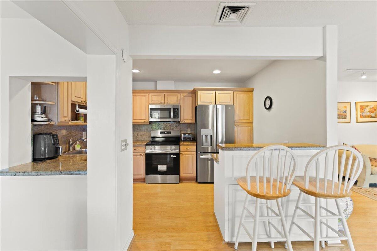 A kitchen features light wood cabinets, stainless steel appliances, and a breakfast bar with chairs — 233 Rio Vista Circle # 233, Atlantis FL 33462, ATLANTIS, FL