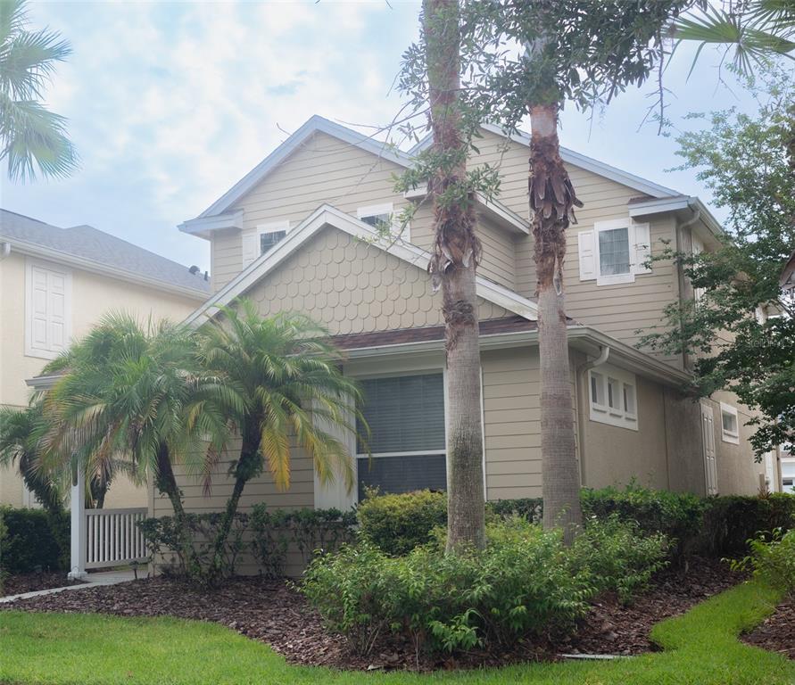 A two-story tan house with a shingled gable, palm trees, and a front porch — 20065 HERITAGE POINT DRIVE, TAMPA, FL