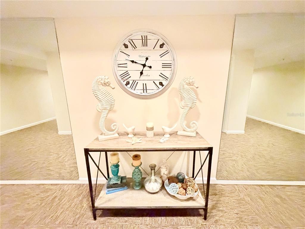 A console table with decor sits between two large mirrors below a wall clock — 7430 SUNSHINE SKYWAY LANE S UNIT 501, ST PETERSBURG, FL