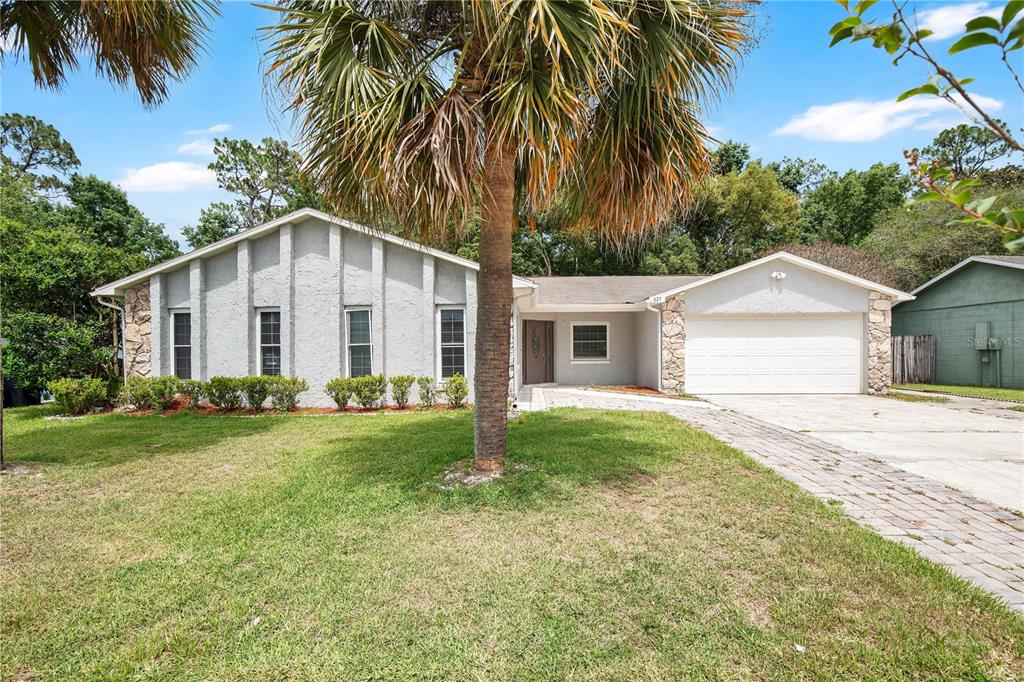 A single-story house with a gray stucco exterior, stone accents, and a paved driveway — 427 ELKWOOD LANE, ORLANDO, FL