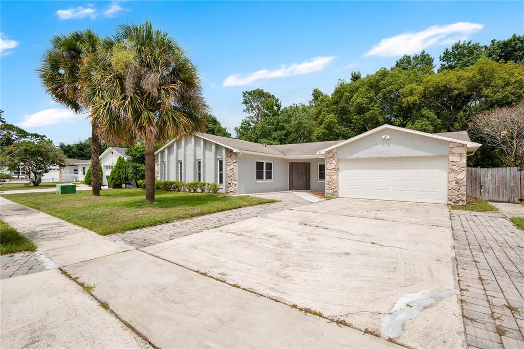 A single-story house with a concrete driveway, stone accents, and a large palm tree — 427 ELKWOOD LANE, ORLANDO, FL