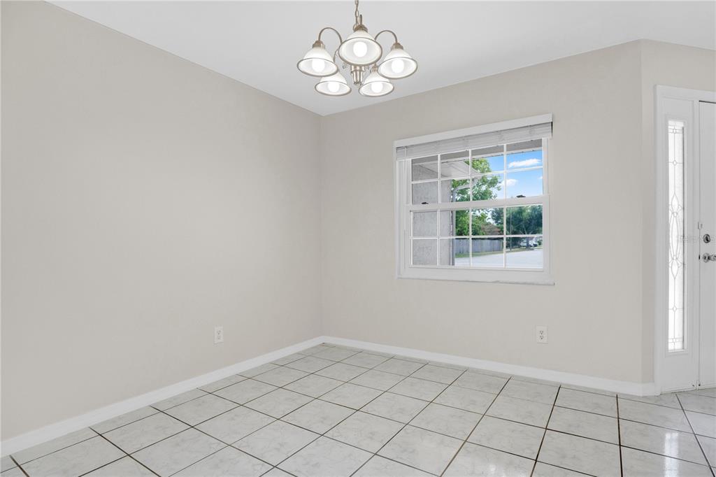 A dining area with light tile flooring, a chandelier, and a window overlooking the outdoors — 427 ELKWOOD LANE, ORLANDO, FL
