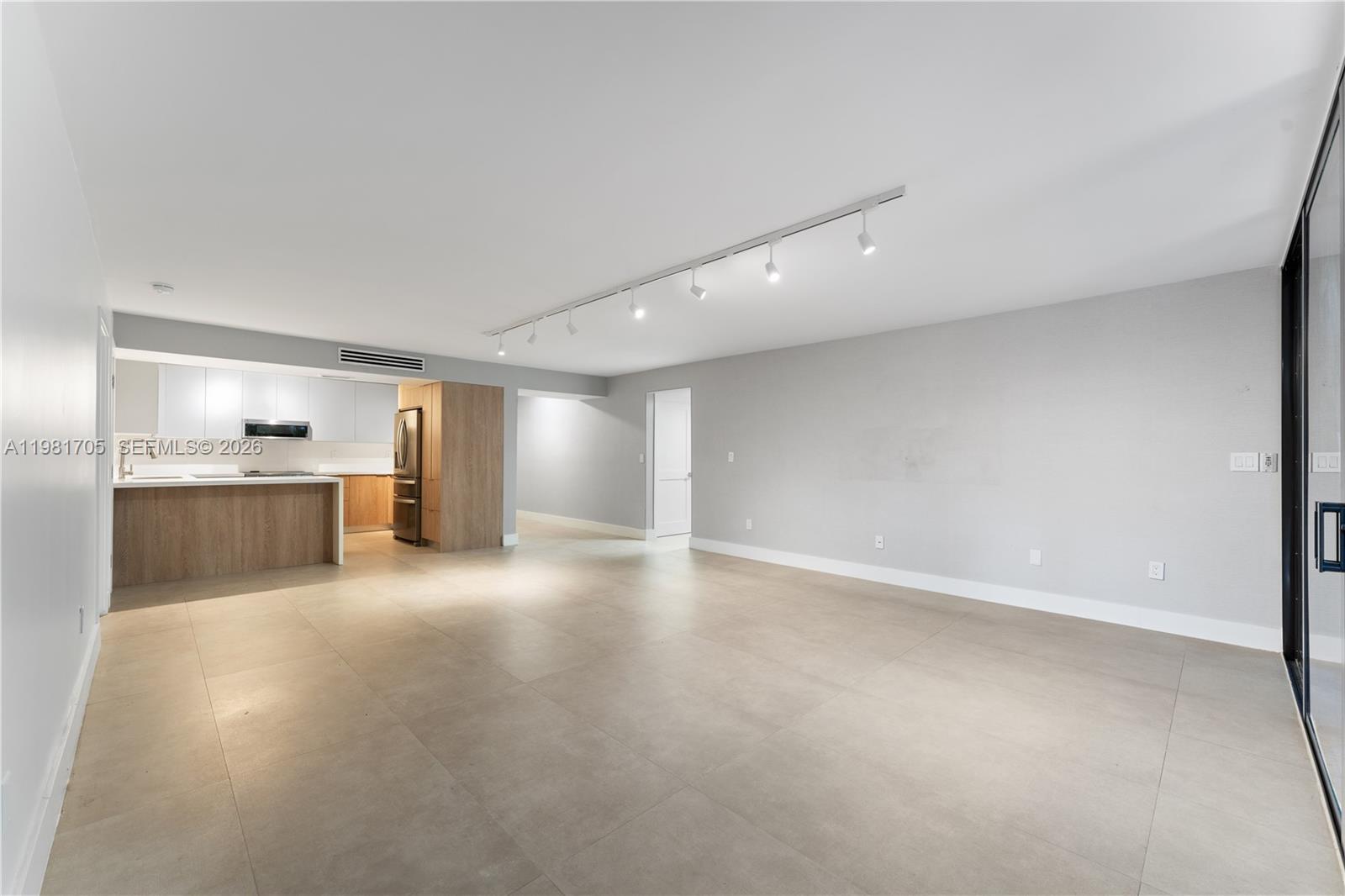 An open-concept living area features large light-colored floor tiles, a kitchen, and track lighting — 55 Ocean Lane Dr # 1031, Key Biscayne FL 33149, KEY BISCAYNE, FL