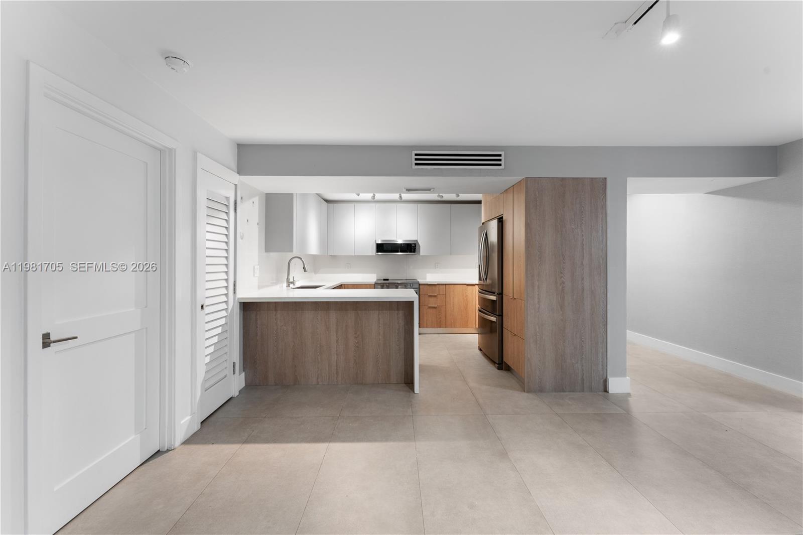 A modern kitchen features wood-toned lower cabinets, white upper cabinets, and a peninsula counter — 55 Ocean Lane Dr # 1031, Key Biscayne FL 33149, KEY BISCAYNE, FL