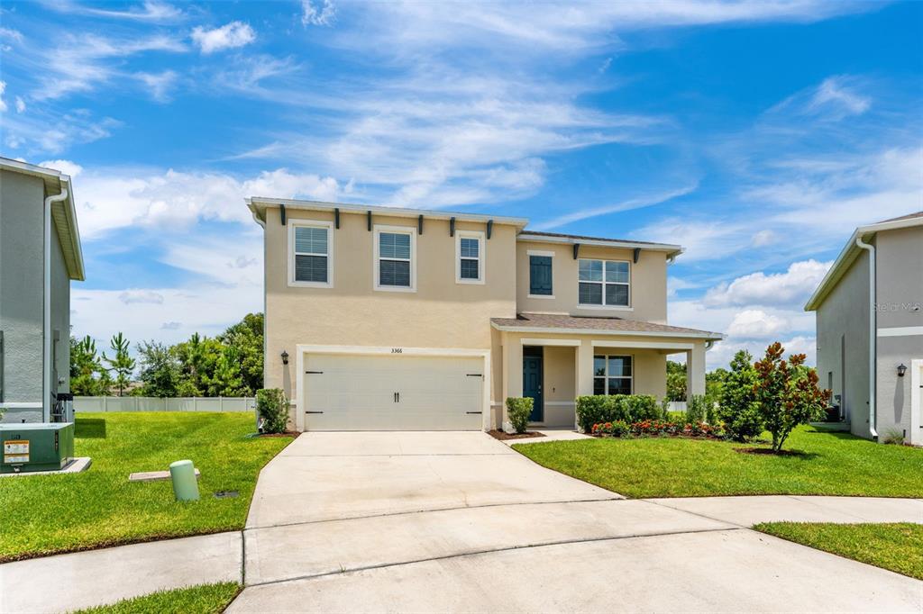 A two-story suburban house with a beige stucco exterior, a two-car garage, and a driveway — 3366 EASTGROVE TERRACE, SANFORD, FL