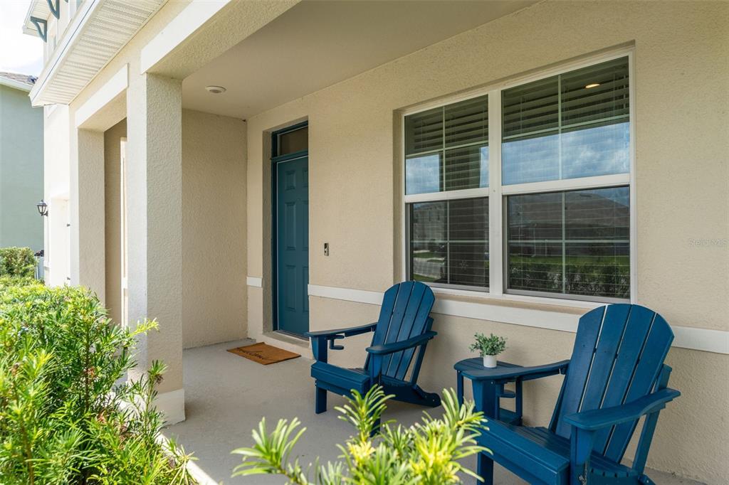 A covered front porch features two blue Adirondack chairs and a small side table — 3366 EASTGROVE TERRACE, SANFORD, FL