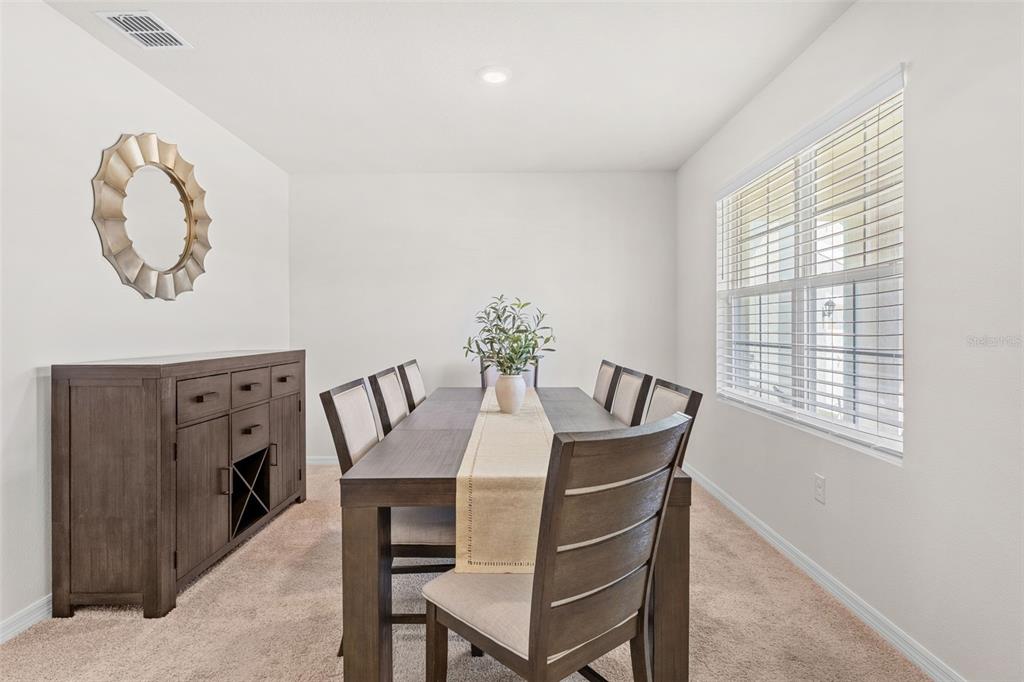 A dining room features a dark wood table, matching chairs, and a coordinating sideboard cabinet — 3366 EASTGROVE TERRACE, SANFORD, FL