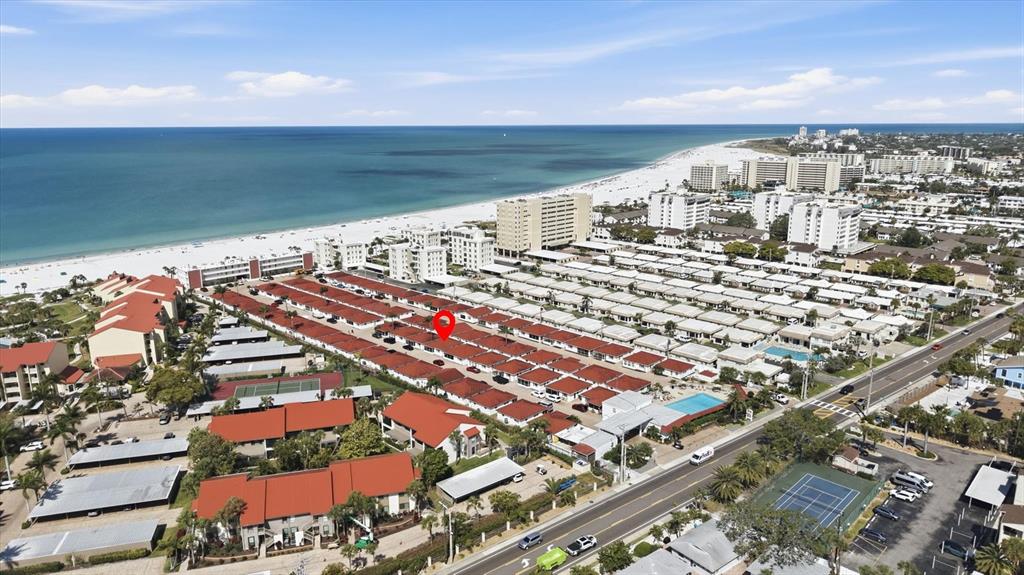 An aerial view shows a residential complex with red-roofed buildings near a sandy beach — 6154 MIDNIGHT PASS ROAD UNIT 7C, SARASOTA, FL