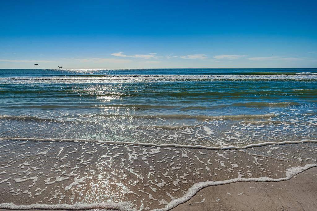 A view of ocean waves washing onto a sandy beach under a clear blue sky — 6154 MIDNIGHT PASS ROAD UNIT 7C, SARASOTA, FL