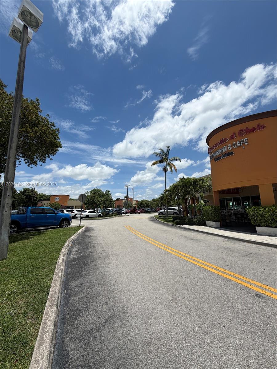 A paved road leads toward a shopping center with a restaurant under a blue sky — 11735 SW 147th Ave #38, Miami FL 33196, MIAMI, FL