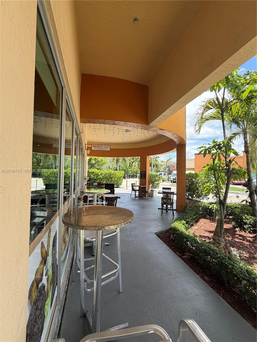 An outdoor patio area features metal tables and chairs under a curved, orange-painted overhang — 11735 SW 147th Ave #38, Miami FL 33196, MIAMI, FL
