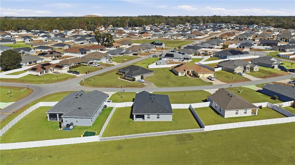 An aerial view shows a suburban neighborhood with several single-family homes and white vinyl fences — 4810 SE 91ST PLACE, OCALA, FL