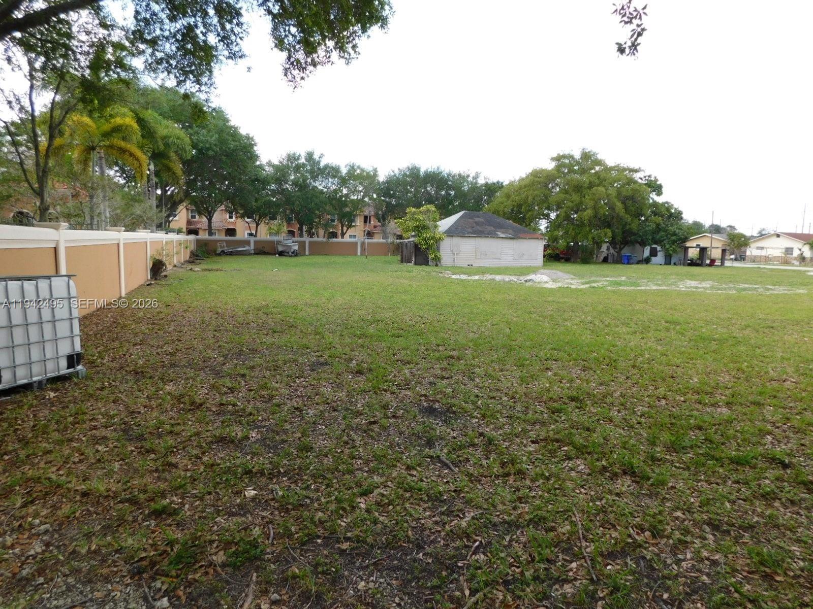 A large, grassy vacant lot features a small shed and a perimeter wall — 5830 Liberty St, Hollywood FL 33021, HOLLYWOOD, FL