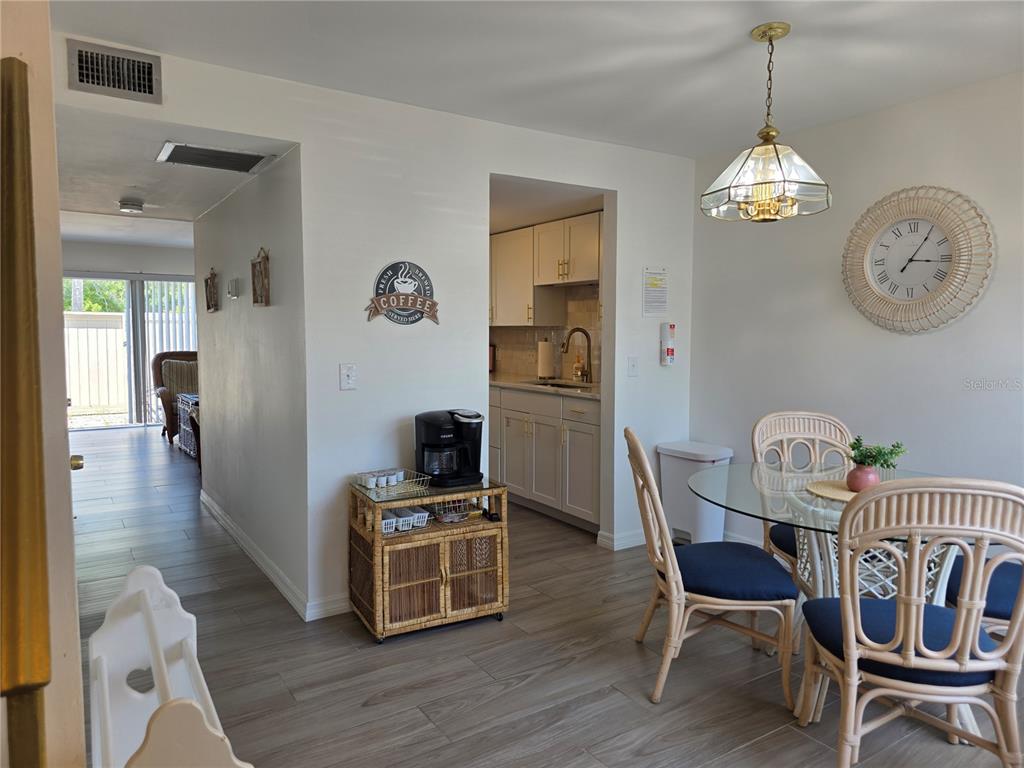 A dining area with a glass table and rattan chairs leads into a small kitchen — 4215 E BAY DRIVE UNIT 1403, CLEARWATER, FL