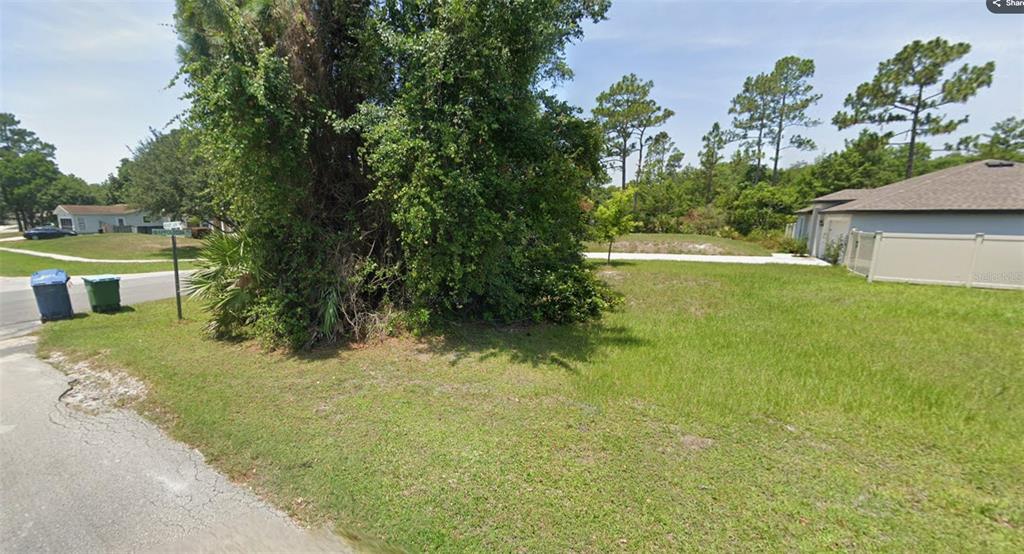 A vacant, grassy residential lot features a large tree and borders a paved sidewalk — 2624 BECKWITH STREET, DELTONA, FL