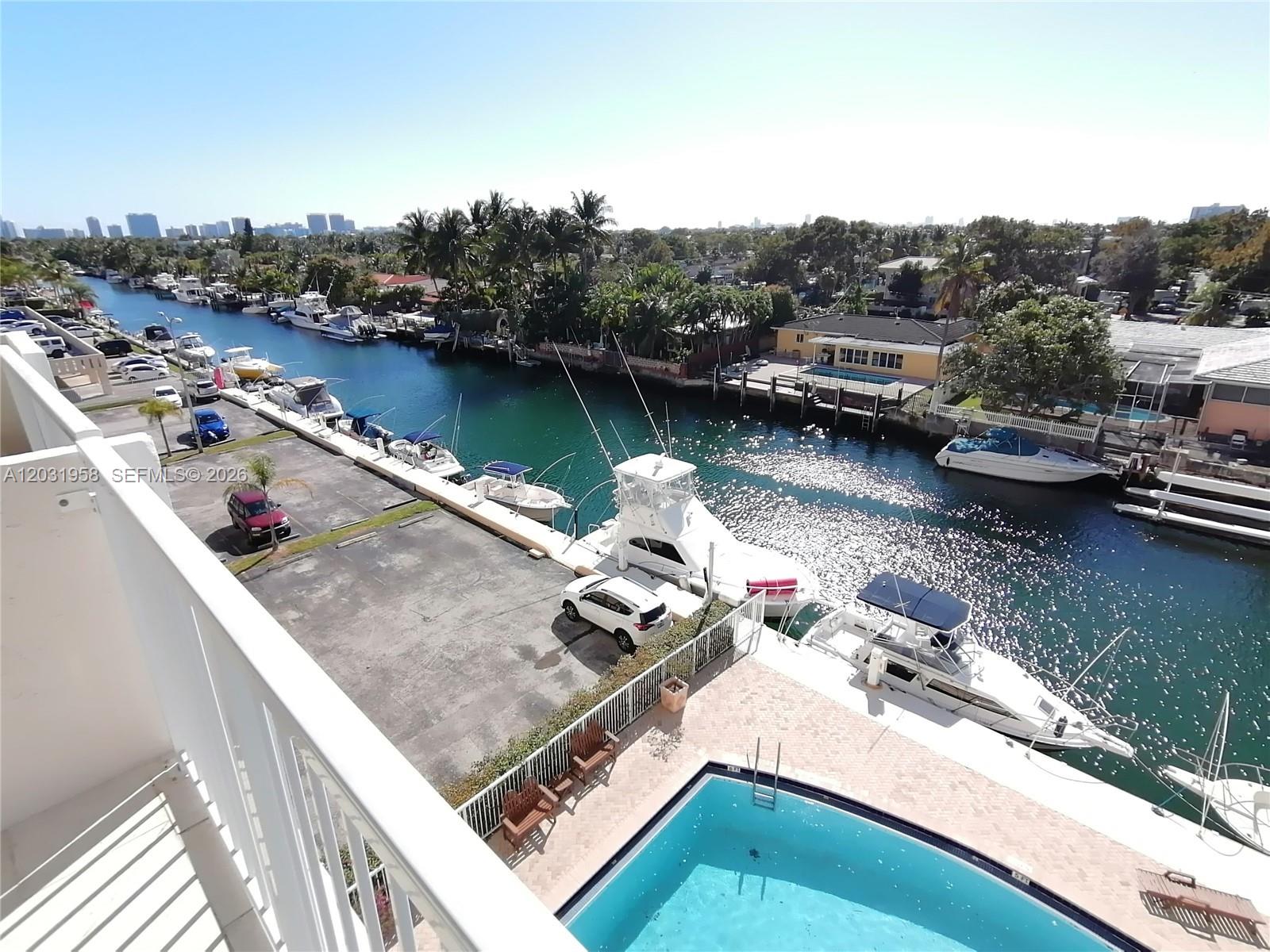 An elevated view shows a swimming pool, a parking lot, and boats docked in a canal — 2020 NE 135th St # 506, North Miami FL 33181, NORTH MIAMI, FL