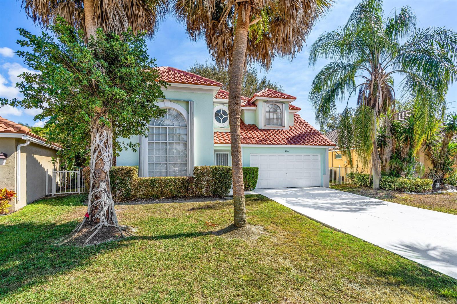 A light green two-story house with a red tile roof and a white garage door — 2746 Linkside Drive, Wellington FL 33414, WELLINGTON, FL