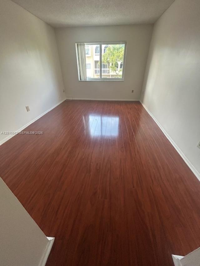 An empty room features light-colored walls, a single window, and dark wood-look flooring — 7740 Camino Real # 306, Miami FL 33143, MIAMI, FL