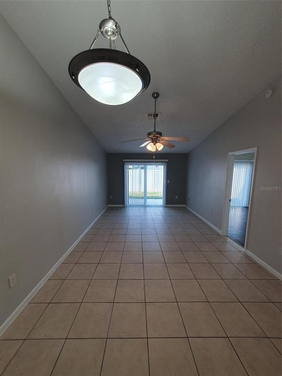 A long, tiled room features a pendant light, a ceiling fan, and sliding glass doors — 1893 ORANGE BOULEVARD WAY, PALM HARBOR, FL