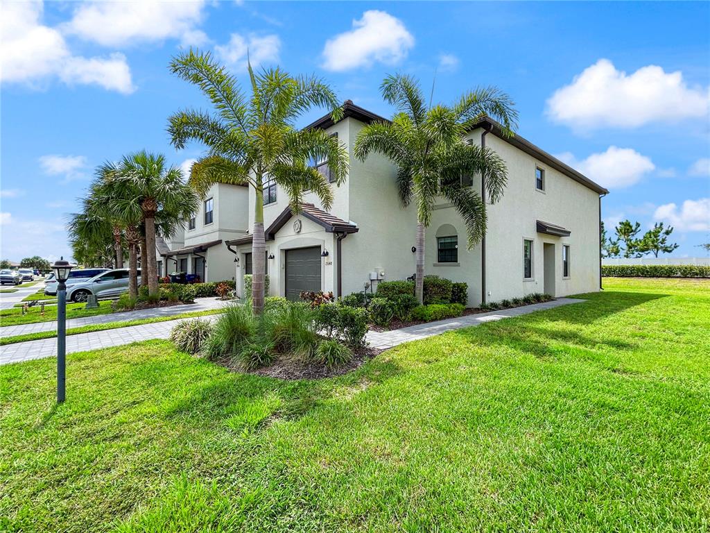 A two-story stucco townhouse with a garage, palm trees, and a paved driveway — 15148 LYLA TERRACE, BRADENTON, FL
