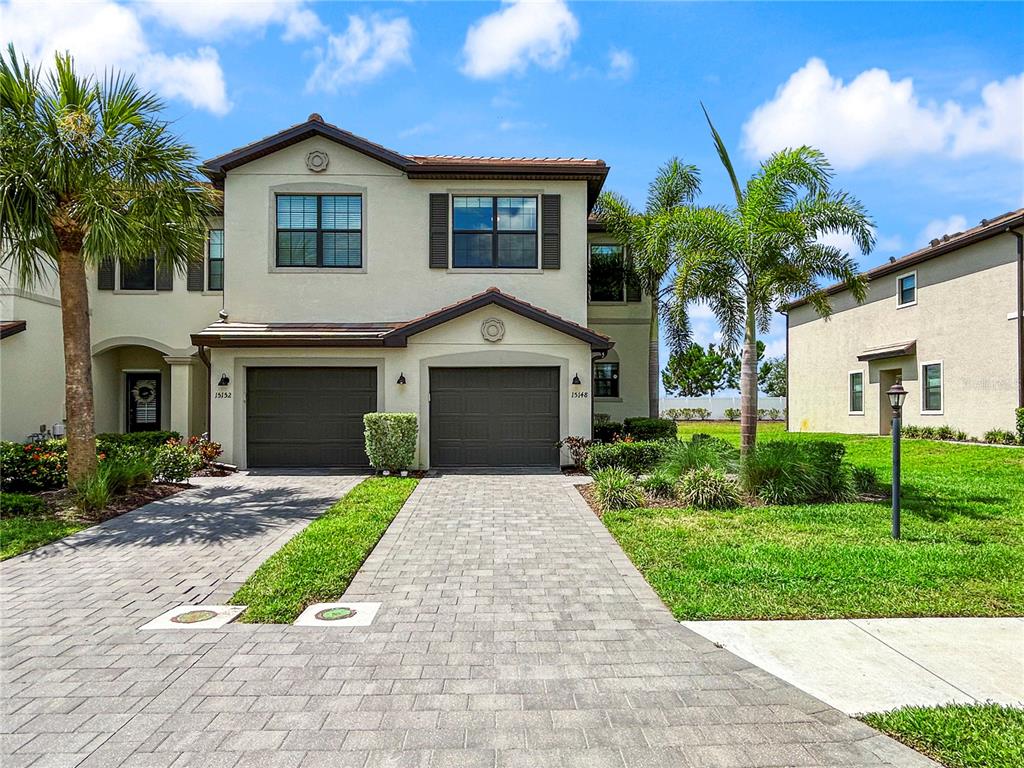 A two-story house with a paver driveway, two garage doors, and palm trees in front — 15148 LYLA TERRACE, BRADENTON, FL