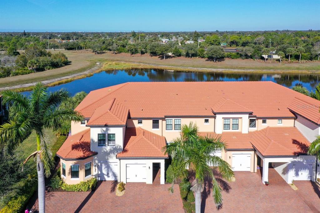 An aerial view of a multi-unit residential building with a tiled roof and brick driveway — 23149 BANBURY WAY UNIT 201, VENICE, FL