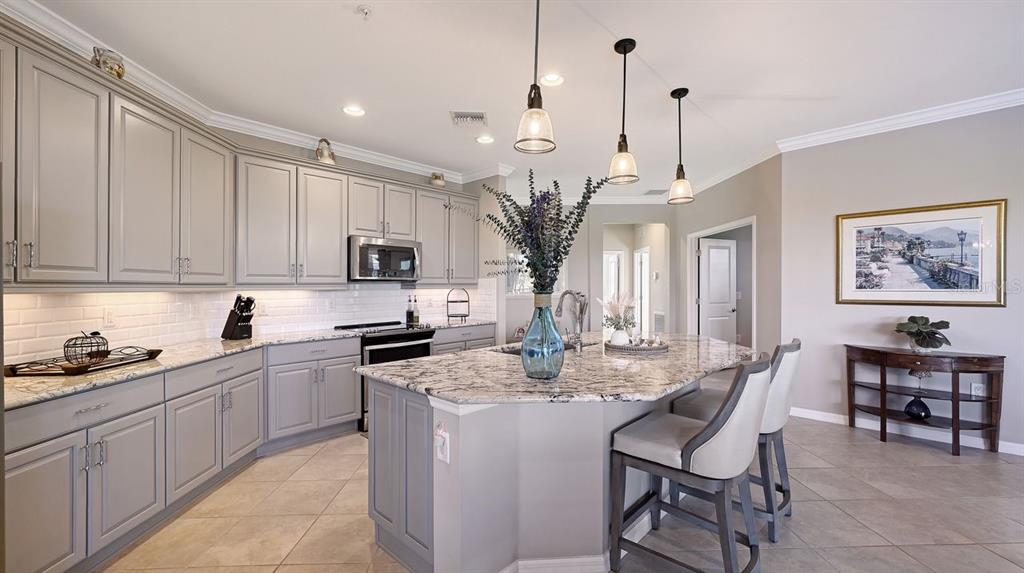 A kitchen with gray cabinets, granite countertops, a center island, and three pendant lights — 23149 BANBURY WAY UNIT 201, VENICE, FL