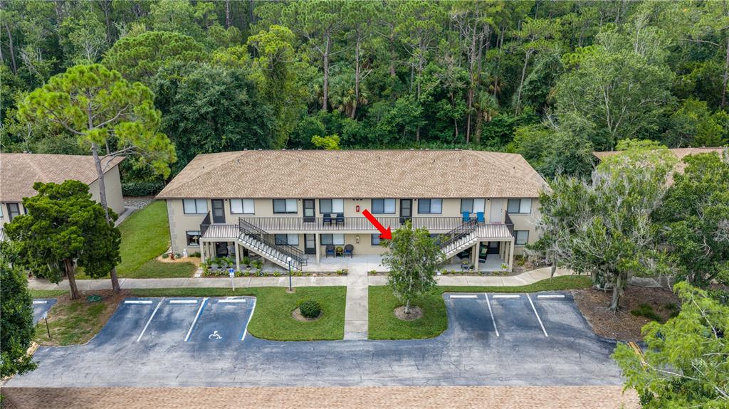 An aerial view shows a two-story apartment building with a parking lot and surrounding trees — 1601 BIG TREE ROAD UNIT 803, DAYTONA BEACH, FL