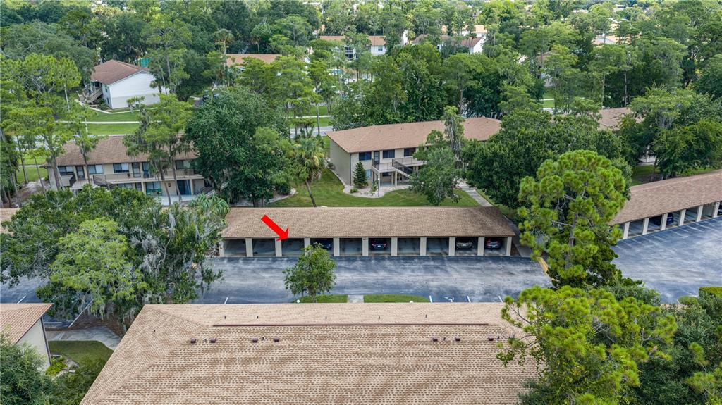 An aerial view shows a residential complex with a covered parking structure and surrounding trees — 1601 BIG TREE ROAD UNIT 803, DAYTONA BEACH, FL