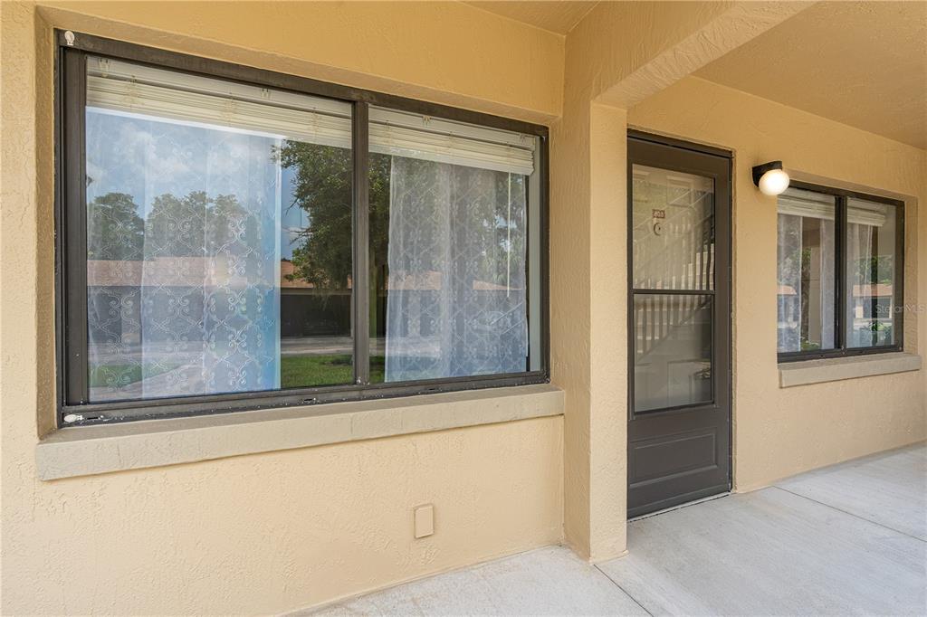 A beige exterior wall features a large window, a dark door, and an outdoor light fixture — 1601 BIG TREE ROAD UNIT 803, DAYTONA BEACH, FL