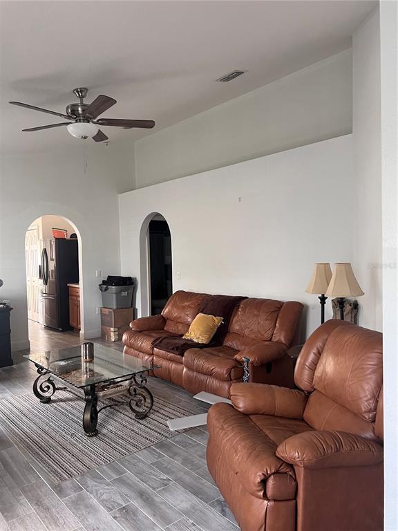 A living room features a leather sofa and armchair, a glass coffee table, and arched doorways — 3460 BELLERICAY LANE, LAND O LAKES, FL