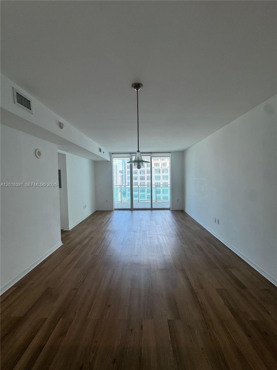 An empty living room features wood-look flooring, white walls, and a balcony with city views — 951 N Brickell Ave # 3001, Miami FL 33131, MIAMI, FL