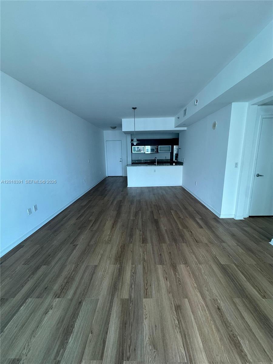 An open-concept living area features wood-look flooring and a kitchen with a breakfast bar — 951 N Brickell Ave # 3001, Miami FL 33131, MIAMI, FL